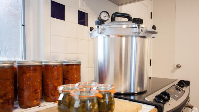 Home Canning jalapenos in jars and a batch of chili with a pressure cooker. Food preservation is key to gardening and homesteading. Pressure canning makes food shelf stable. 