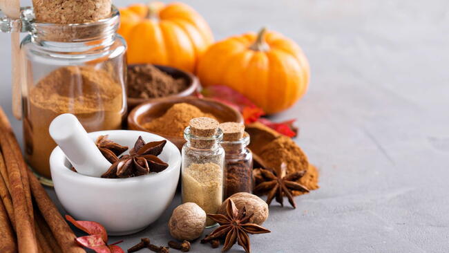 Homemade pumpkin pie spice in a glass jar with the ingredients around it